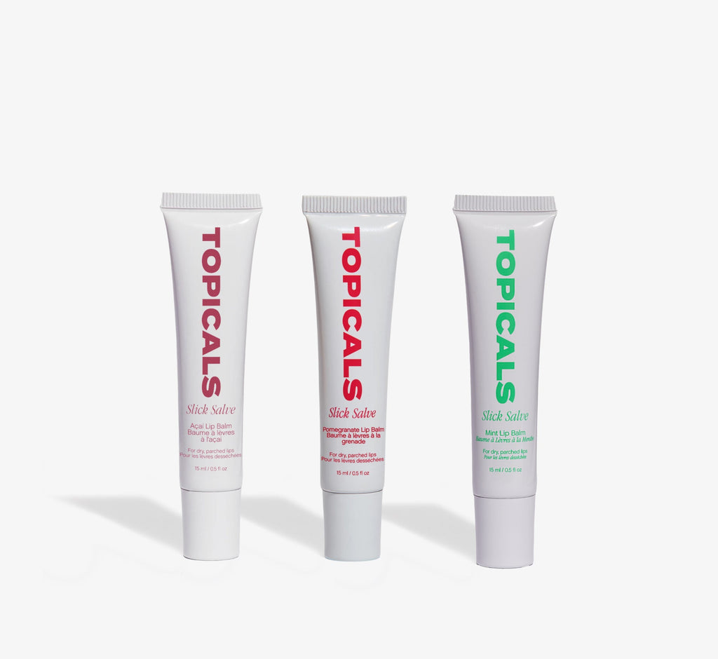 Moisturizing lip balm trio from Topicals Slick Salve in Açaí, Pomegranate, and Mint standing upright side by side on a white background.